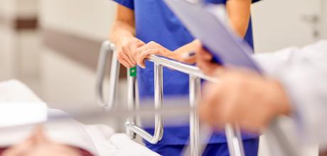 doctor with clipboard and nurse by hospital bed