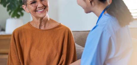 Patient holding hands with a supportive clinician, sat down on a sofa