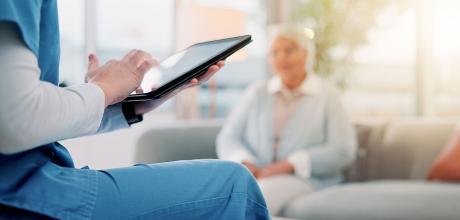 Woman sat on a chair, touching the screen on a tablet
