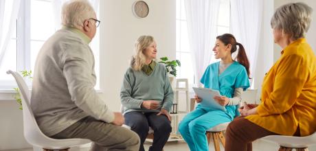 Group of patients with a female clinician sat in chairs in a circle