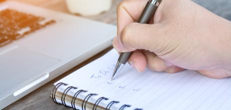 Person writing a 'to do list' on a notepad