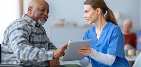 Female clinician sharing information on a digital tablet with a male patient 