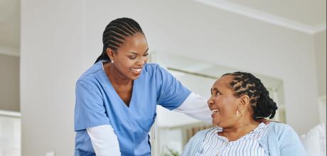 Clinician smiling to a woman sat in a chair, who is looking up at her and smiling back