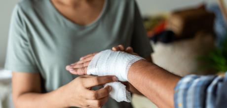 Woman dressing a patient's wound on their hand