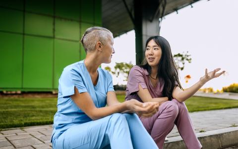 Two female nurses talking outside