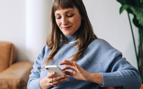 Woman sat on a chair, touching the screen on her phone