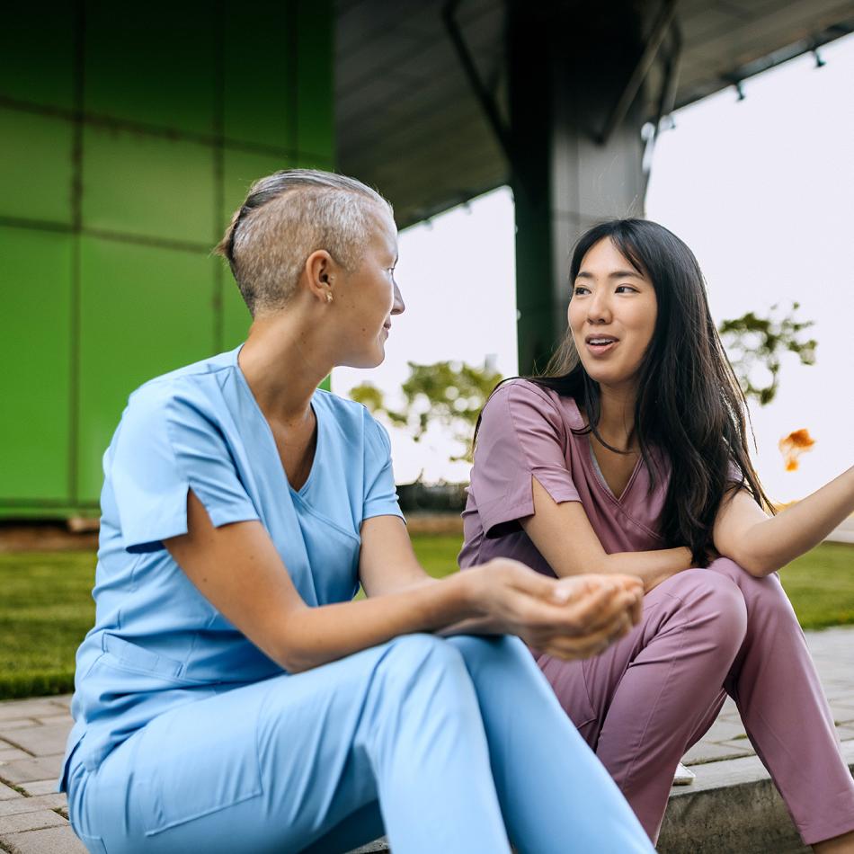 Two female medical staff sitting outside talking