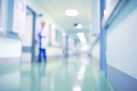 Blurred photograph of a hospital with staff walking in the hallway