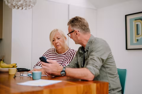 Man and woman sitting down at a table, looking at a phone