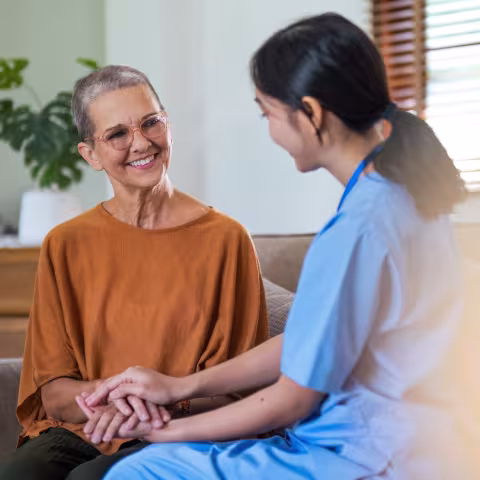 Patient holding hands with a supportive clinician, sat down on a sofa
