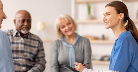 Female clinician talking with a group of people in a white room