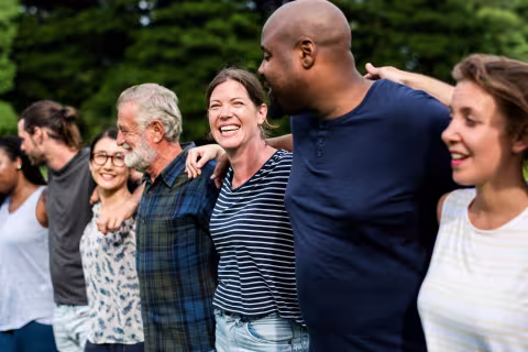 Inclusive group of people outside holding onto eachother 
