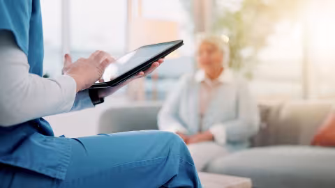 Woman sat on a chair, touching the screen on a tablet