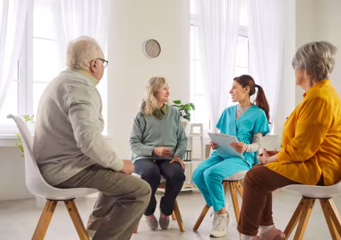 Group of patients with a female clinician sat in chairs in a circle
