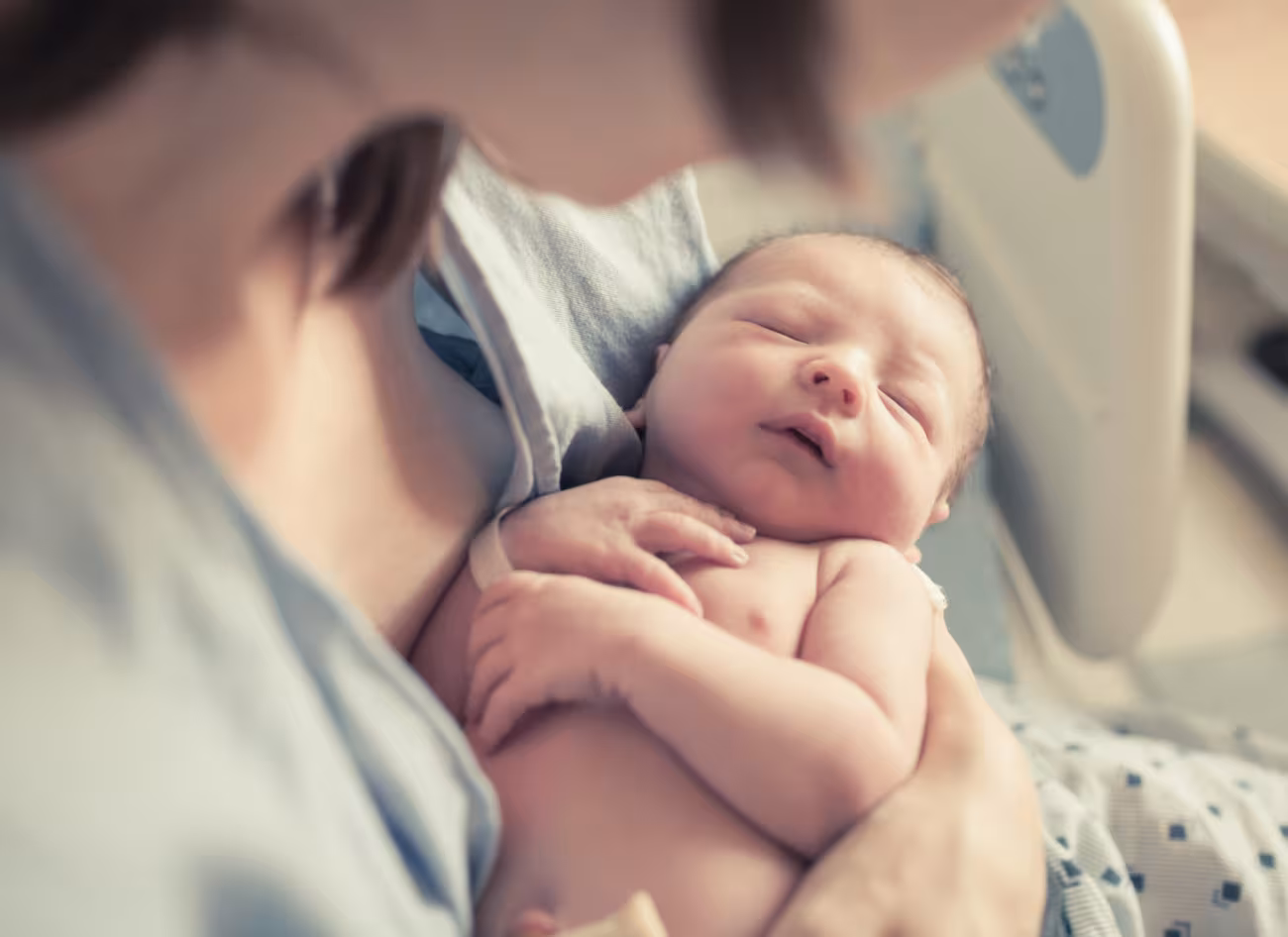 Sleeping new-born baby cradled gently by an adult.