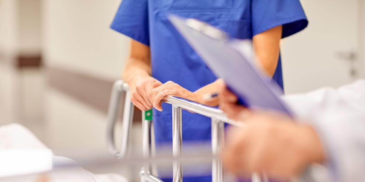 doctor with clipboard and nurse by hospital bed