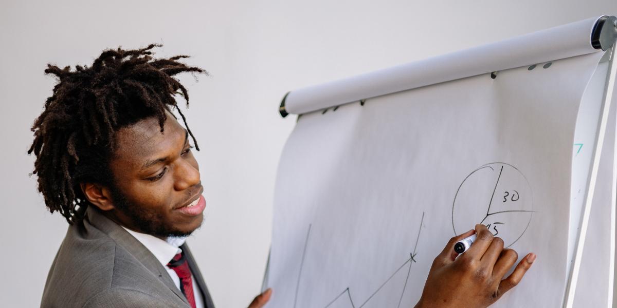 Photograph: Focused man in a suit drawing business charts on a flip chart.