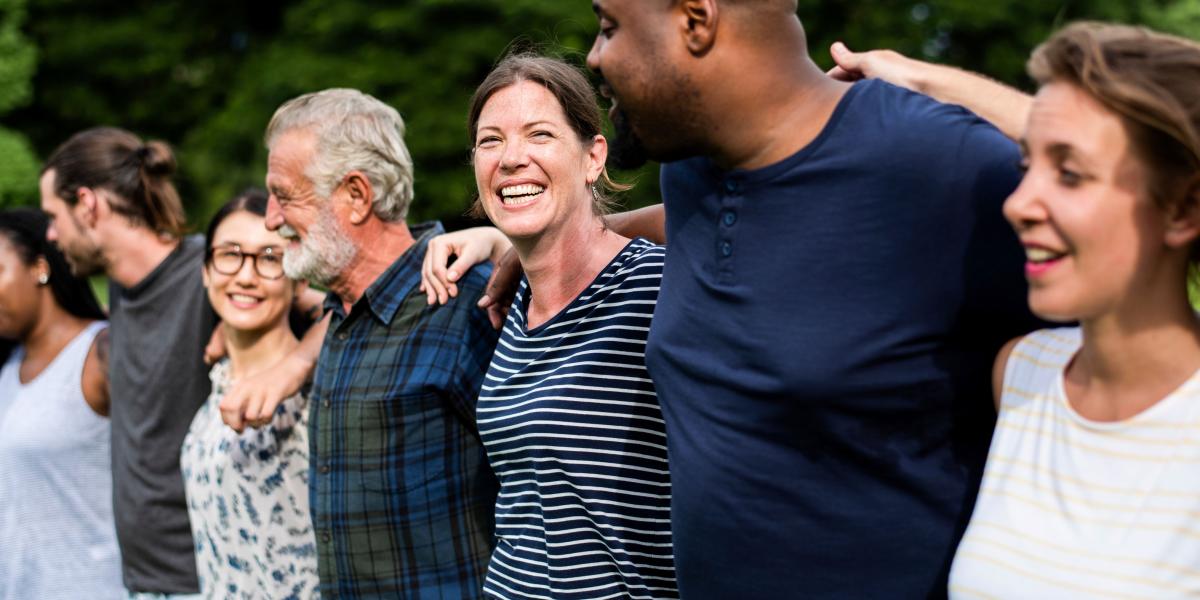 Inclusive group of people outside holding onto eachother 