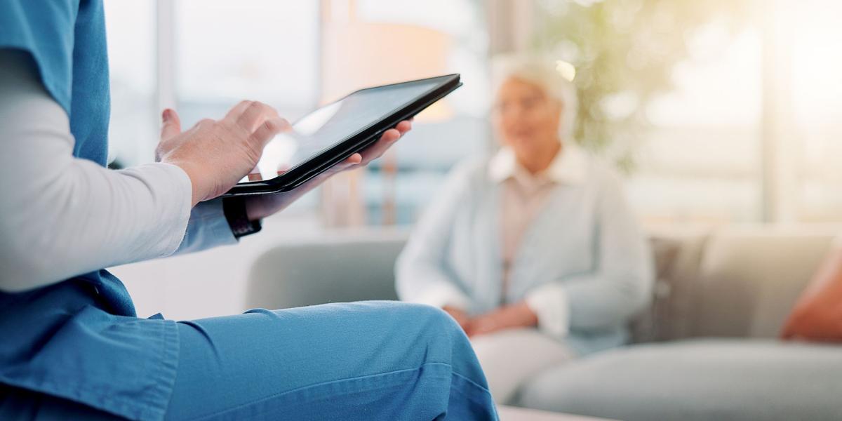 Woman sat on a chair, touching the screen on a tablet