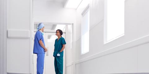 two nurses in scrubs talking in hospital corridor 