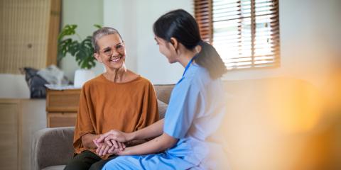 Woman holding hands with nurse as they talk