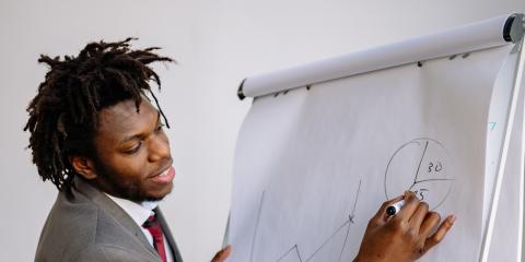Photograph: Focused man in a suit drawing business charts on a flip chart.