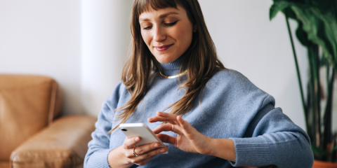 Woman sat on a chair, touching the screen on her phone