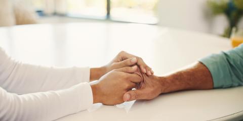 People with tanned skin tone holding hands over a table 