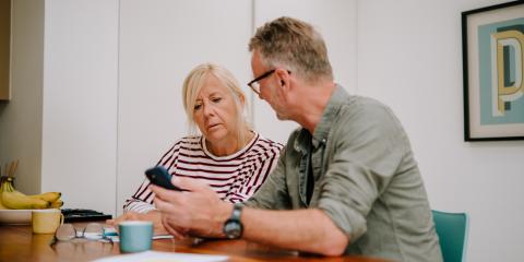 Man and woman sitting down at a table, looking at a phone