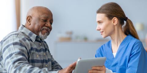 Female clinician showing a male patient information on a digital tablet