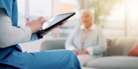 Woman sat on a chair, touching the screen on a tablet